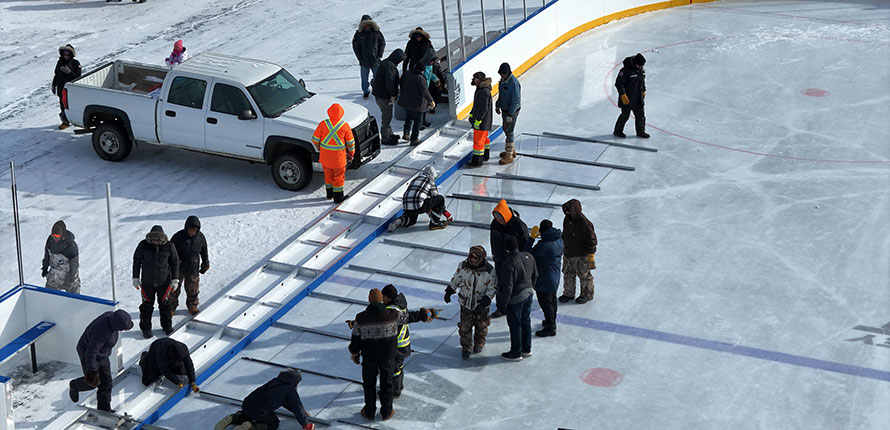 Deline community members reconstructing boards on hockey rink